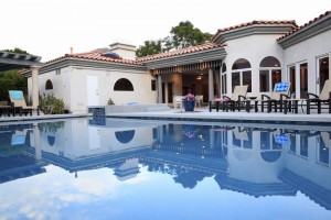 Spanish Mediterrian architecture. Evening on the luxurious back pool and patio.  Reflections of lights,house and lounge chairs.  No people.